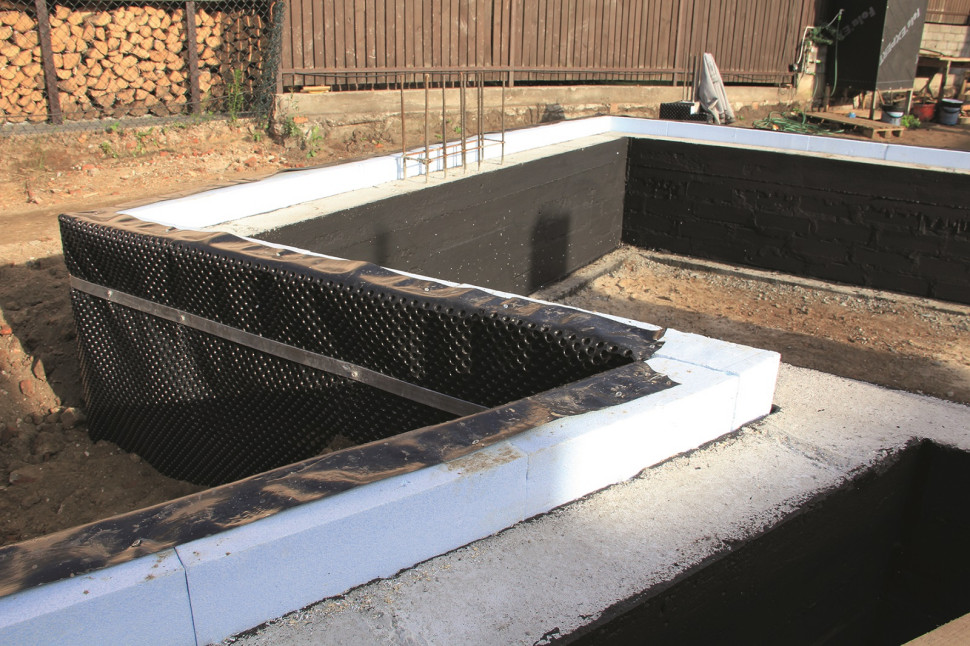 Ściany fundamentowe z pionową hydroizolacją z masy bitumicznej, ocieplone od zewnątrz niebieskim styropianem typu fundament, zabezpieczonym folią kubełkową