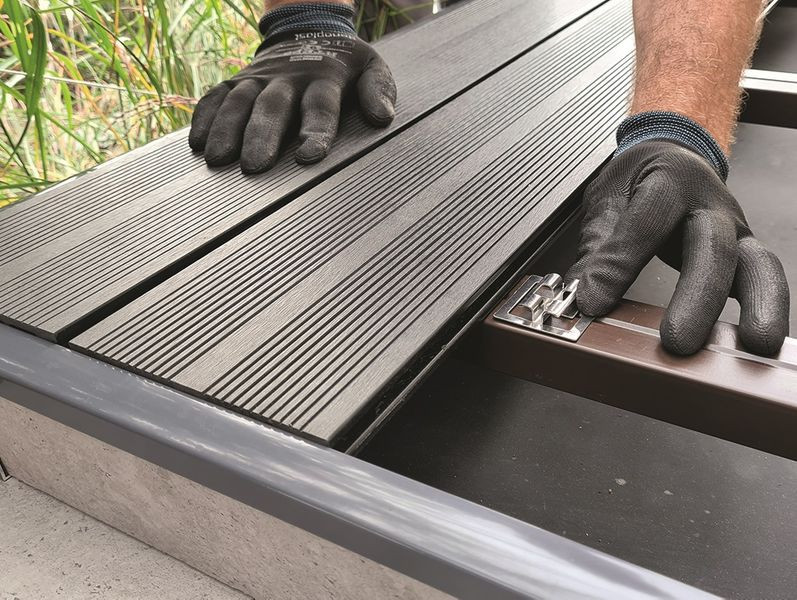 Taras wykończony deskami kompozytowymi ułożonymi na wspornikach montażowych i innych elementach stanowiących kompletny system tarasowy