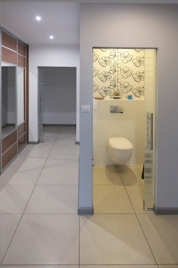 Szklane drzwi do toalety. W ścianach o lekkiej konstrukcji z płytami g-k właściciel zamontował prowadnice