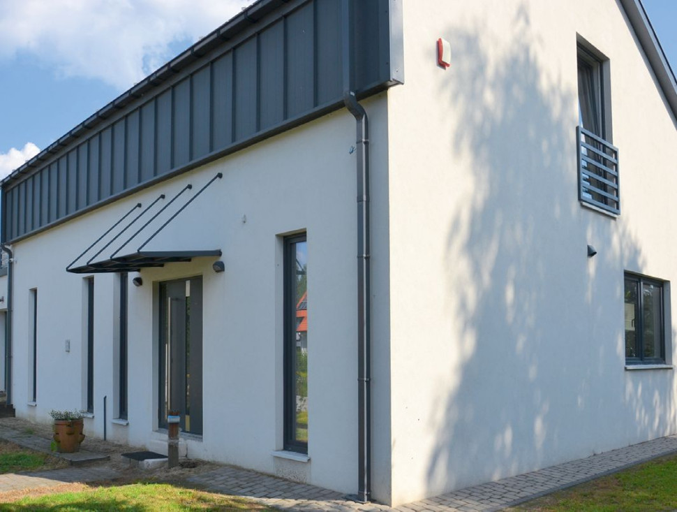 Ozdobą prostej elewacji frontowej są wąskie podłużne okna oraz przeszklone główne wejście, które umieszczono pod małym stalowym daszkiem