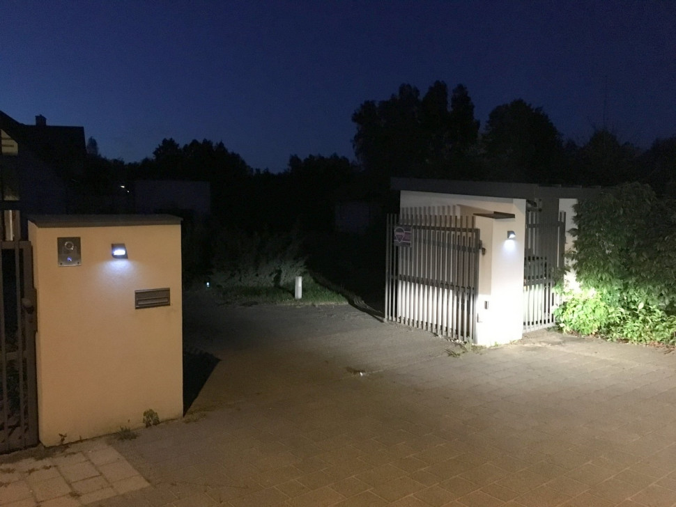 Kinkiety, przymocowane do murków przy furtce i bramie, oświetlają wjazd na posesję, domofon, numer