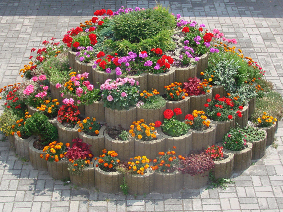 Kilka gazonów w jednym kolorze ułożonych w kształcie piramidy z posadzonymi różnokolorowymi kwiatami. fot. JONIEC® 