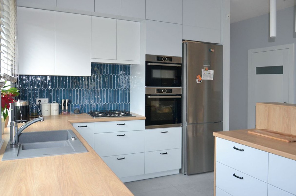 Zabudowę w kuchni właściciele zaprojektowali w kształcie litery L z wyspą