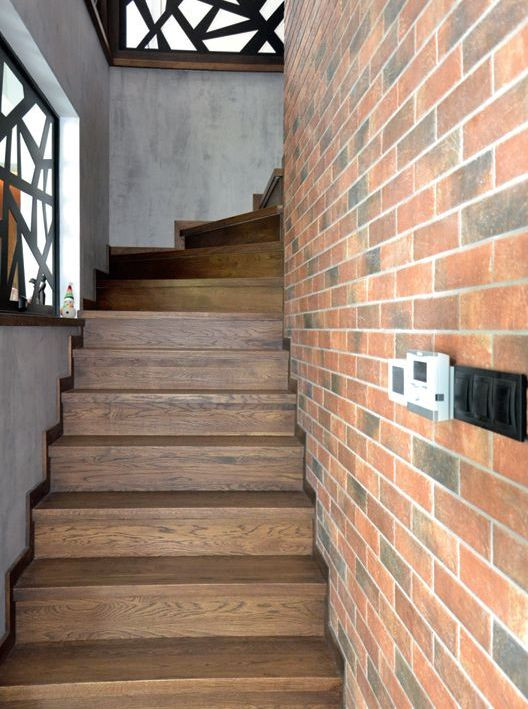 Zabiegowe schody są wykończone drewnem dębowym, ściany - betonem dekoracyjnym, okładziną imitującą cegłę, ażurowymi elementami ze stali pomalowanej proszkowo
