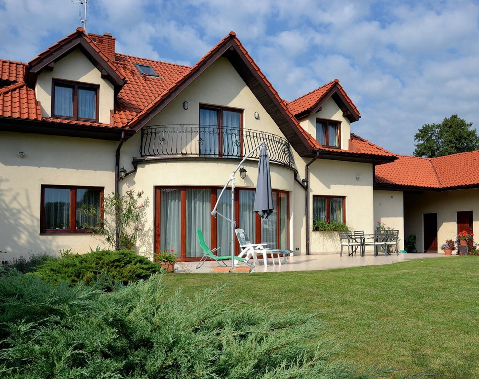 Elewacja z jasnego tynku oraz okna z drewna meranti i szybami klasy P4