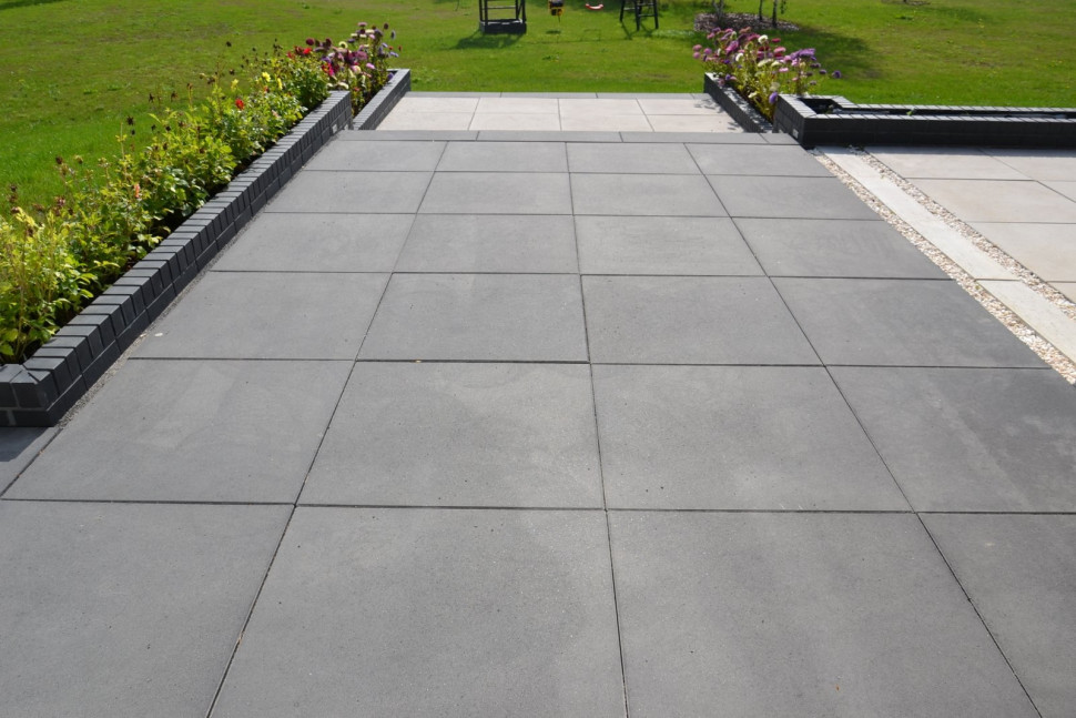 Taras ma ze wszystkich stron schody i donice na kwiaty, wymurowane z cegły klinkierowej