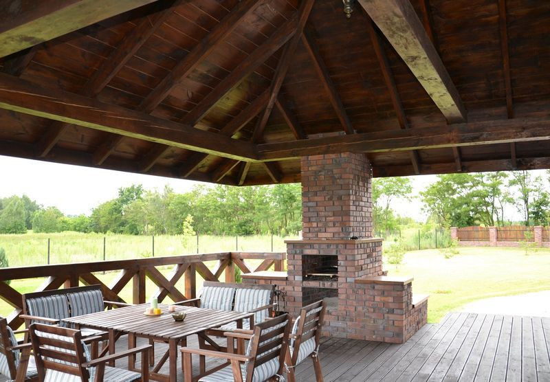 Przy stacjonarnym grillu rozstawiono wygodne meble z drewna