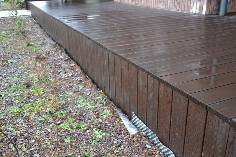 Na granicy drewna i rabat z roślinami ułożono folię kubełkową