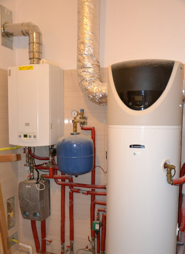 Kotłownia, położona w aneksie garażowym, jest obszerna (7,45 m2) i mieści: dwufunkcyjny kocioł na gaz z sieci, pompę ciepła typu powietrze/woda z wbudowanym zasobnikiem c.w.u. o poj. 200 l, zmiękczacz wody z wodociągu oraz strefę przeznaczoną na pralnię i suszarnię, w której zamontowano umywalkę