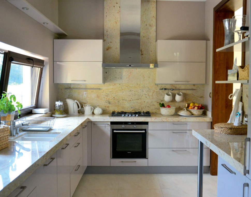 Blaty kuchenne oraz osłonę ściany przy kuchence gazowej wykonano z granitu, natomiast meble – z płyt MDF polakierowanych na biało