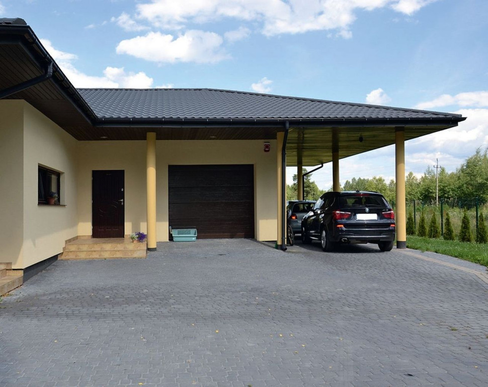 W garażu mieści się tylko jeden samochód, dlatego właściciele ulokowali przy nim, pod dachem, otwartą wiatę.