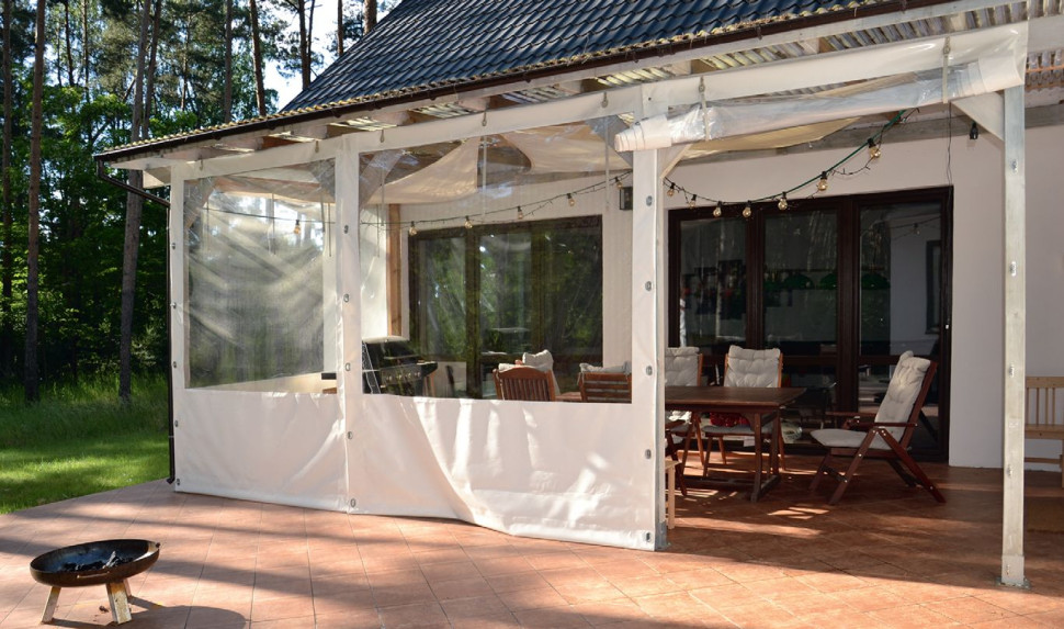Taras i drewniana pergola zadaszona płytami poliwęglanu i żaglem