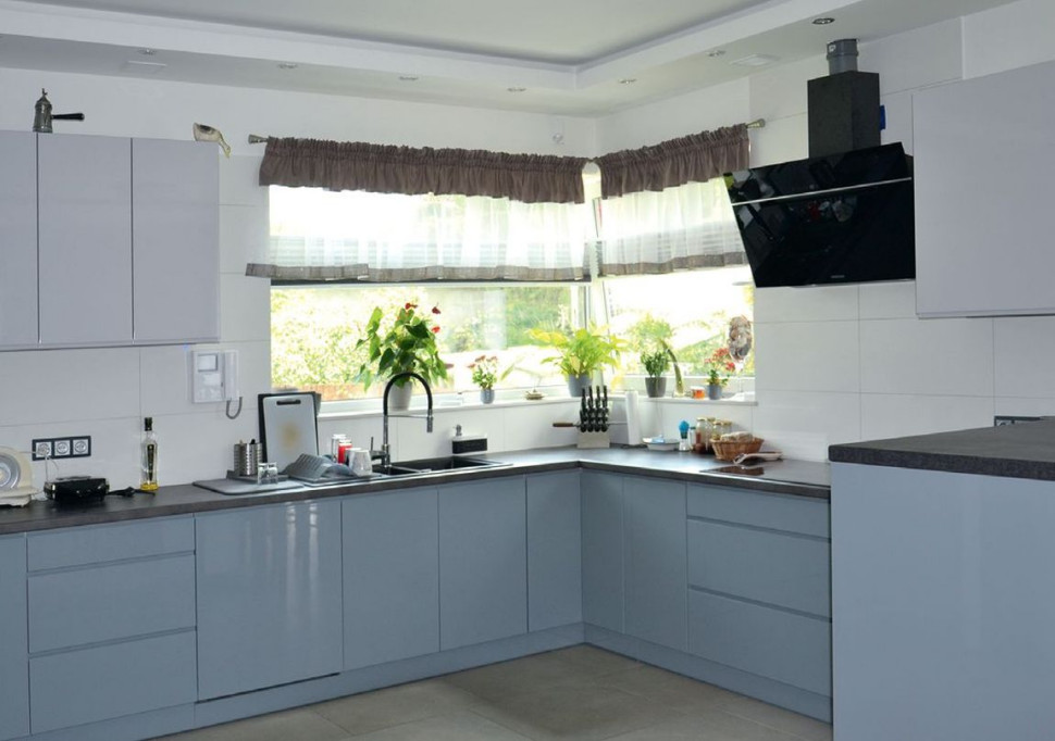 Obszerna kuchnia została umeblowana zabudową w kształcie litery U, z półwyspem na granicy z jadalnią