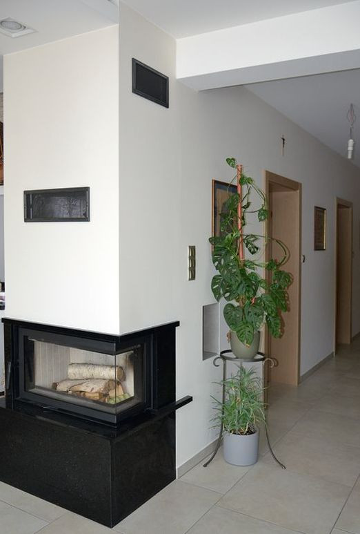 W centrum domu znajduje się kominek z żeliwnym wkładem, rozprowadzającym ciepło grawitacyjnie