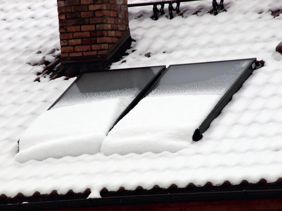Płaskie kolektory słoneczne częściowo przykryte śniegiem