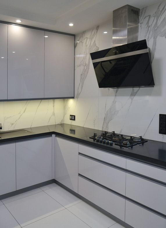 Wielkoformatowe płyty Specchio Carrara i blat z Corianu nadają kuchni elegancji