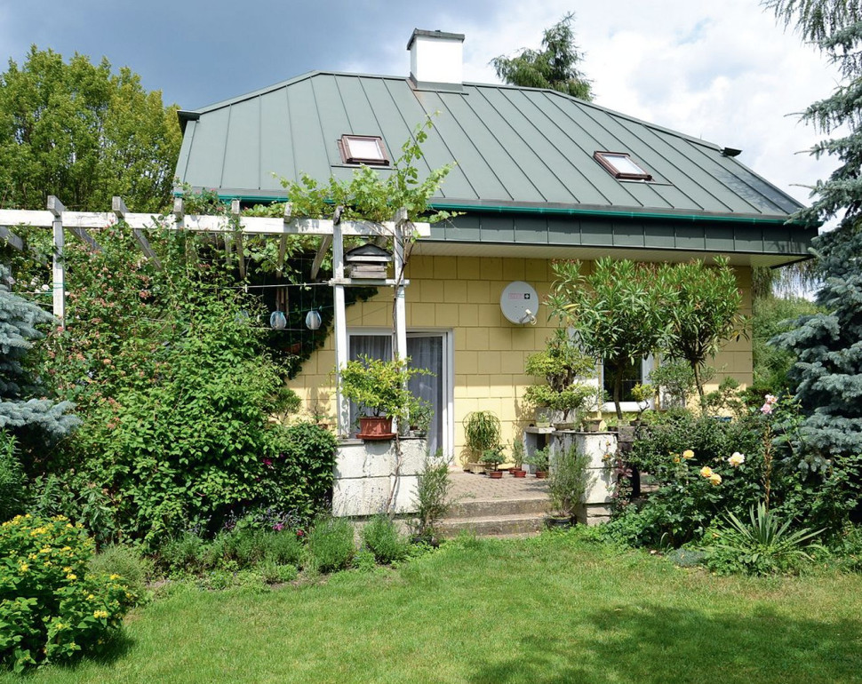 Dwukondygnacyjny dom ma zwartą bryłę i naczółkowy dach