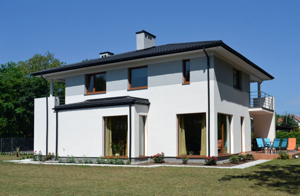 Dwukondygnacyjny budynek z pełnym piętrem przykrywa czterospadowy, wykończony blachodachówką w kolorze antracyt