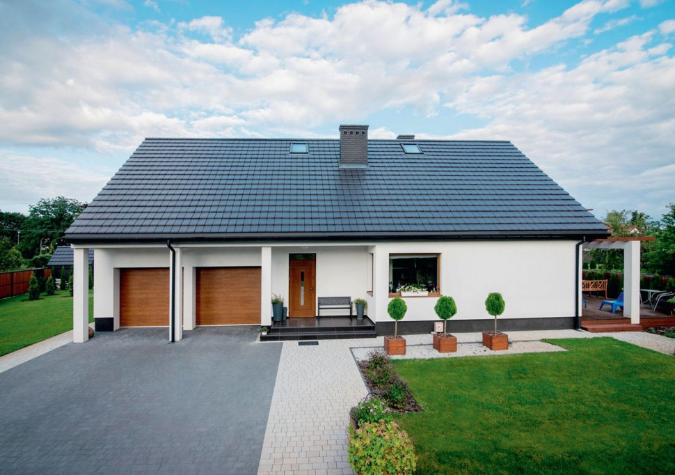 Budynek ma horyzontalną bryłę i stoi na środku niezadrzewionej posesji