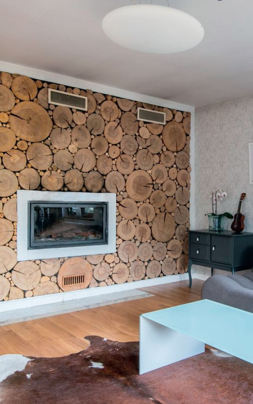 Okładzina ścienna koresponduje z drewnianą podłogą, a biała rama podkreśla efektowną panoramiczną szybę wkładu kominkowego