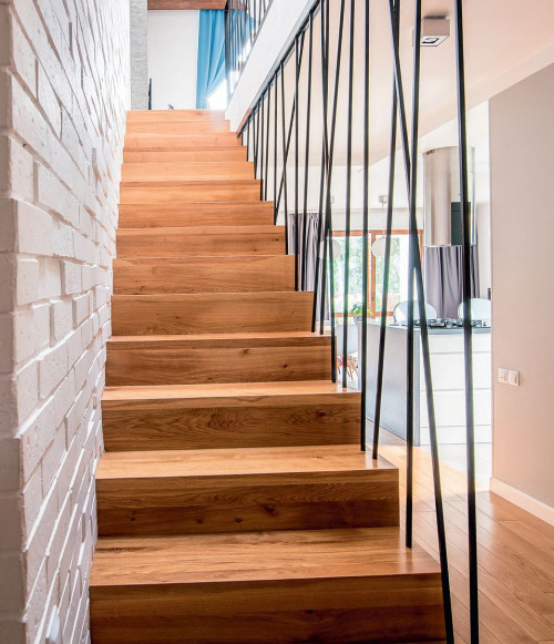 Jednobiegowe schody z drewna dębowego oraz ażurową balustradą z prętów stalowych