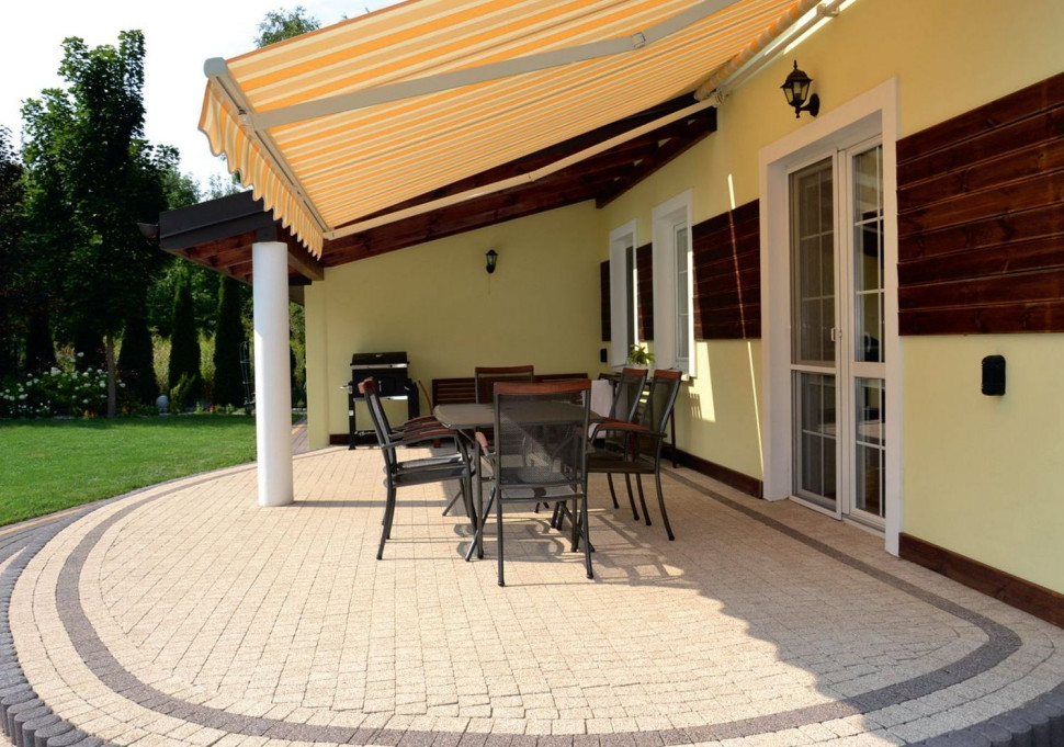 Taras wyłożony kostką betonową zadaszony markizą