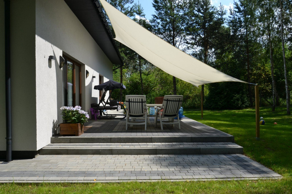 Na taras prowadzą schody, a część nawierzchni osłania płócienny żagiel