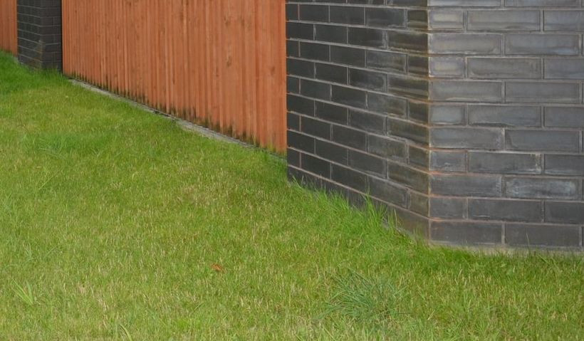 Brak wybrukowanego pasa wzdłuż ogrodzenia utrudnia koszenie trawnika