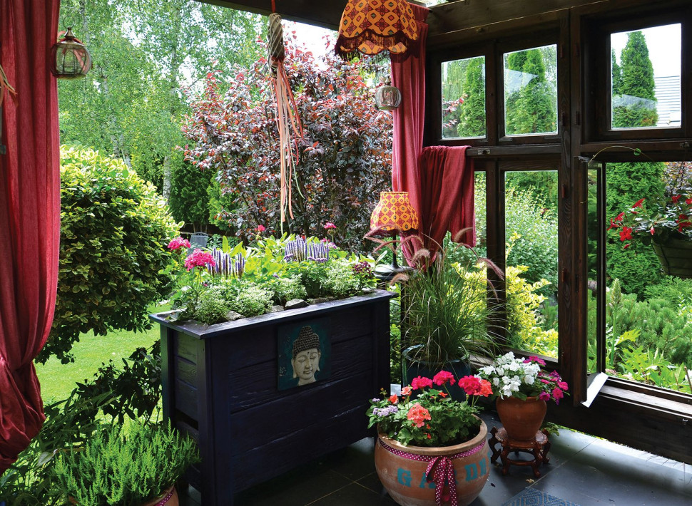Kolorowa aranżacja osłoniętego tarasu - wykorzystano w niej bibeloty, dywaniki, lampy, donice