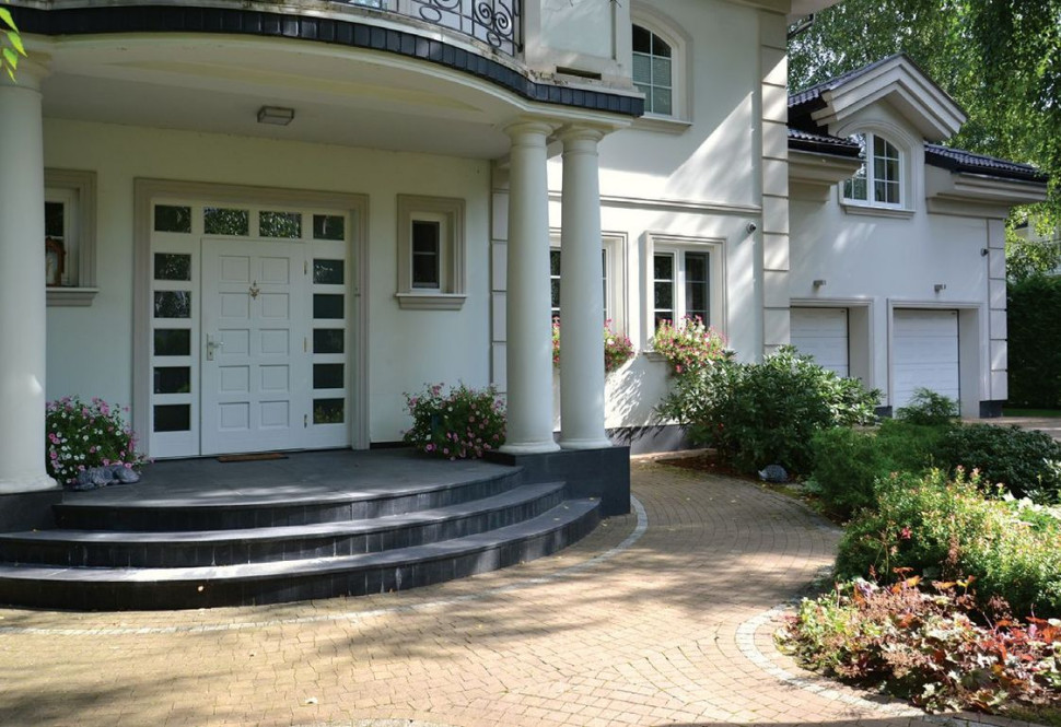 Reprezentacyjną strefę wejściową ozdabia półokrągły ganek i szerokie drzwi okolone doświetlami