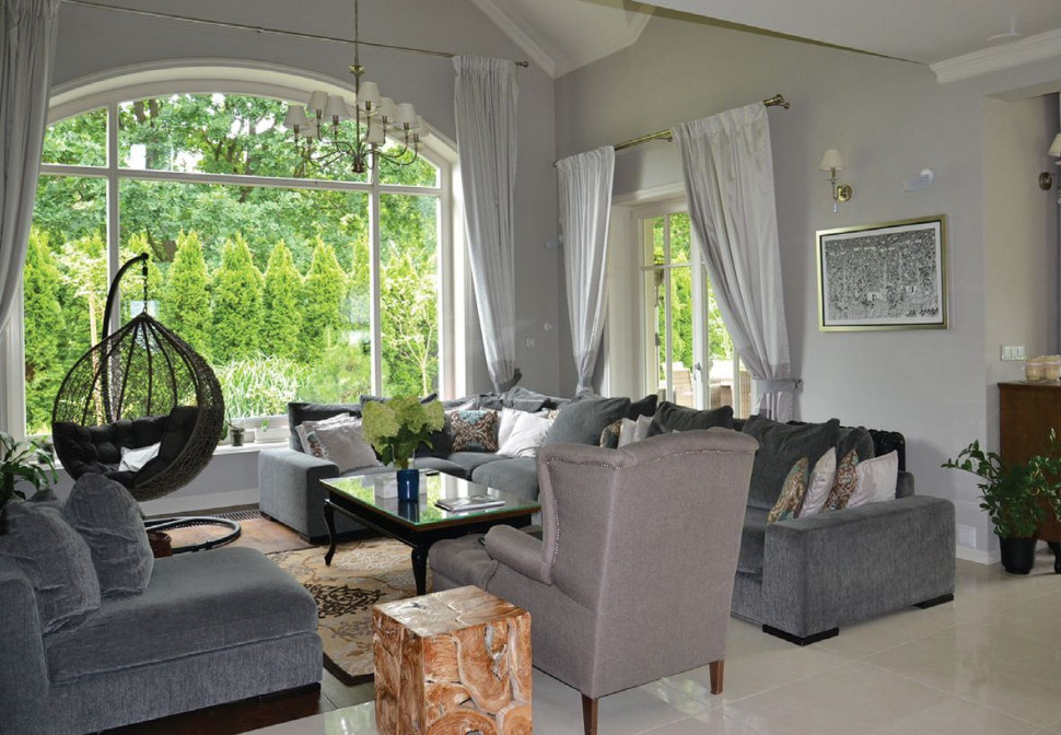 Obszerny salon o wysokości dwóch kondygnacji ozdabia stropodach oraz okno z łukiem