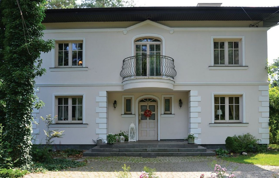 Piętrowa bryła ma symetryczny układ okien, drzwi z łukiem, harmonizujące z kształtem balkonu i kutej balustrady