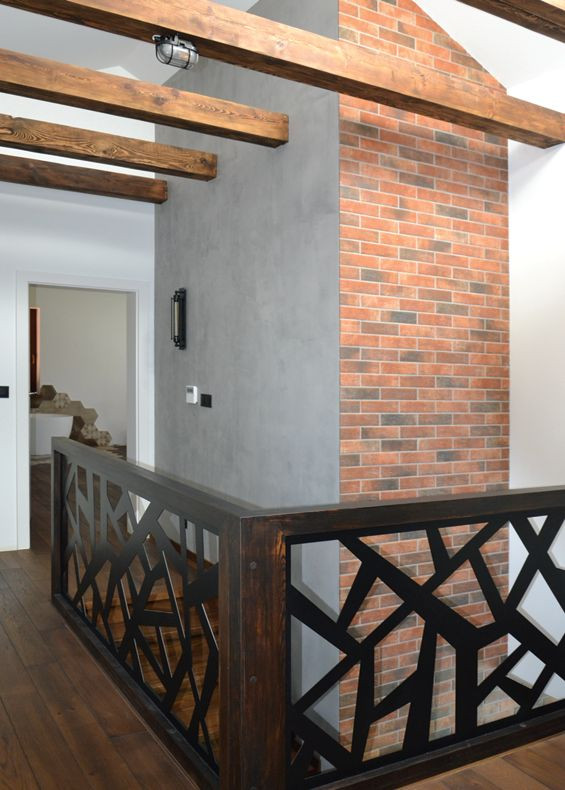 Wzdłuż klatki schodowej ułożono tynk dekoracyjny (szary) i cieniowaną okładzinę klinkierową