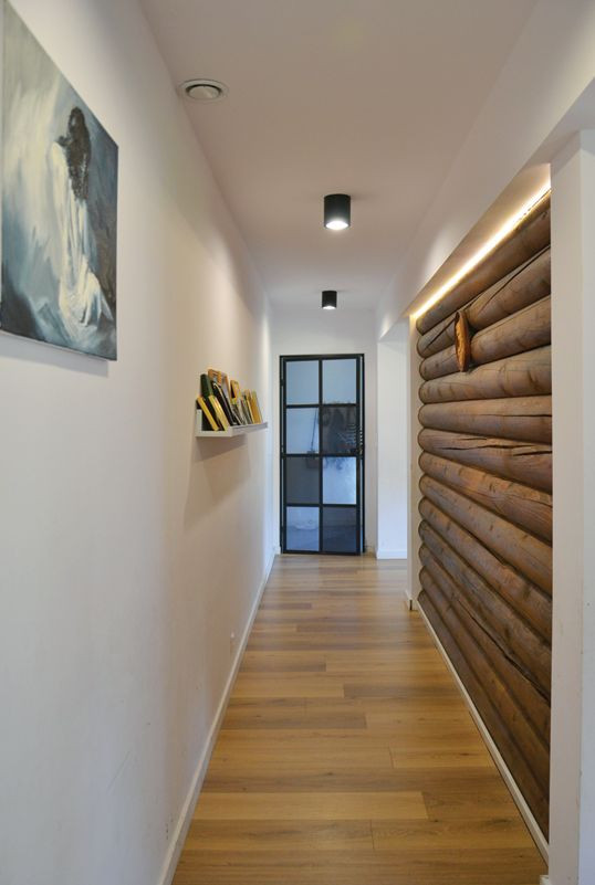 Przegroda z drewna ozdabia długi korytarz, oddzielający strefę dzienną od pomieszczeń prywatnych i technicznych