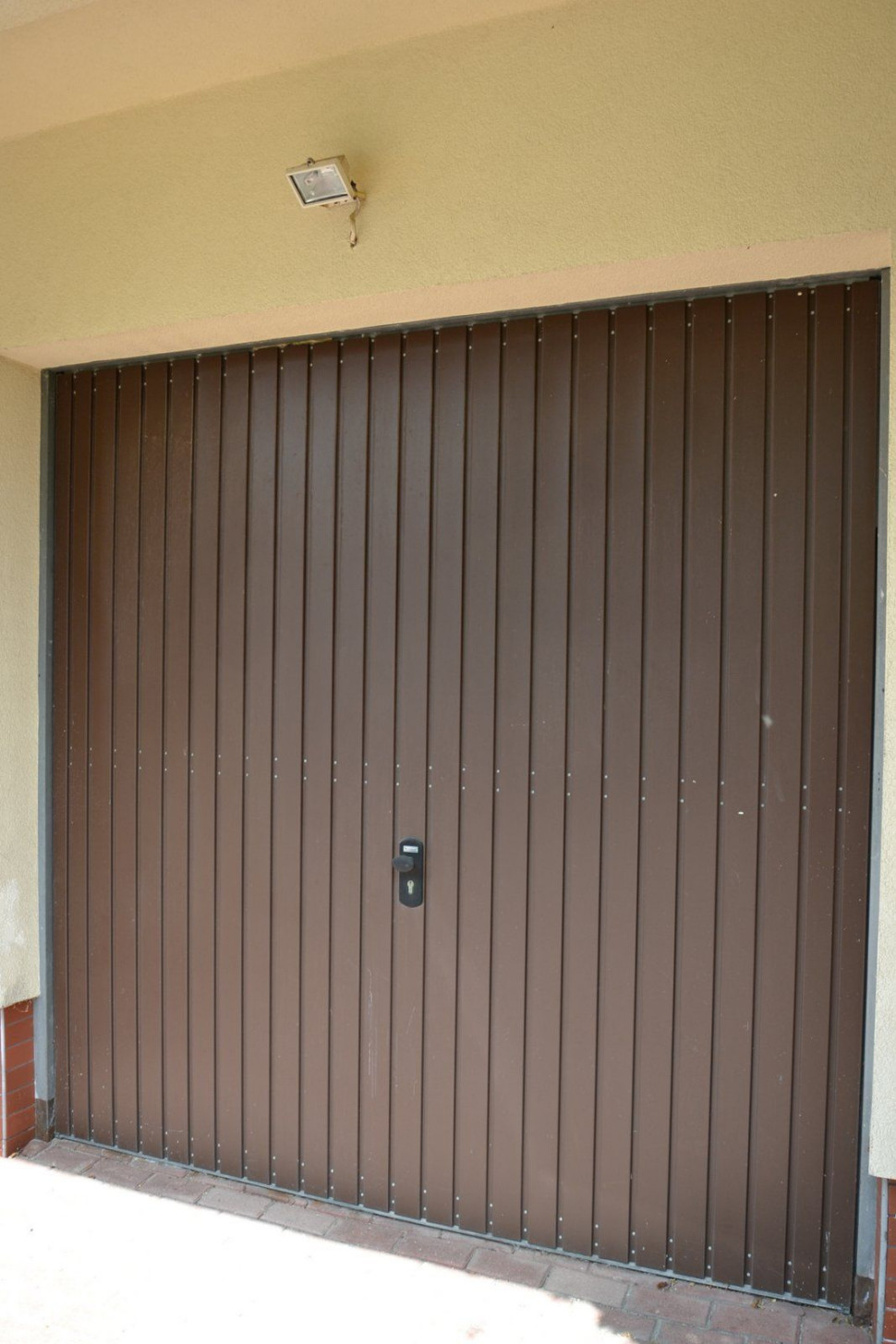 Uchylne płytowe wrota na zewnątrz wykończono przetłaczaną i proszkowo polakierowaną blachą stalową