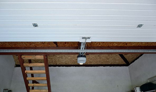 Wrota segmentowe wraz z prowadnicami i napędem układają się pod sufitem antresoli