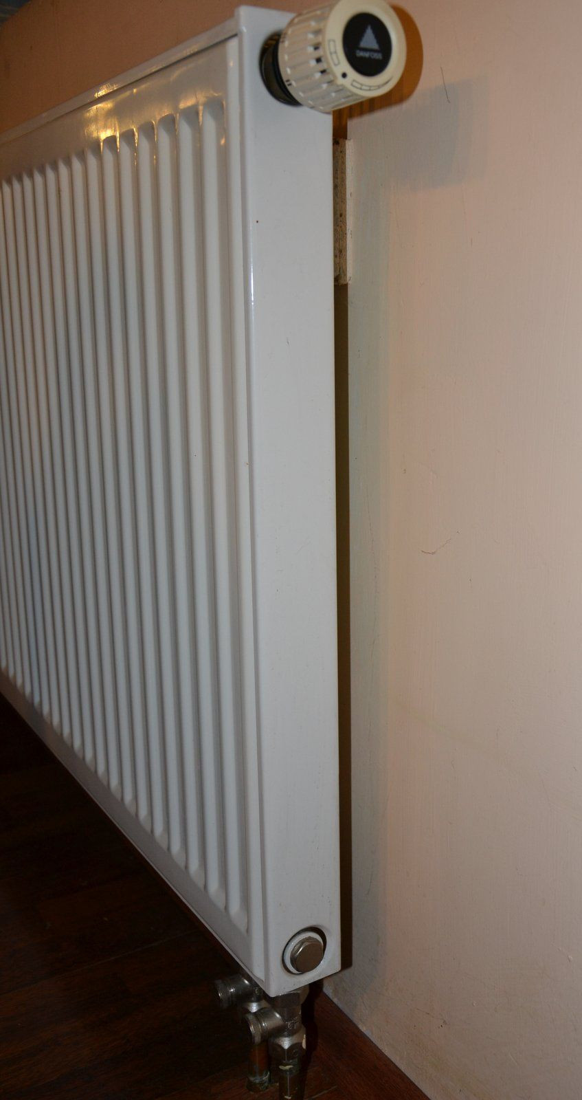 Grzejnik płytowy: rury instalacji c.o. wychodzą z podłogi