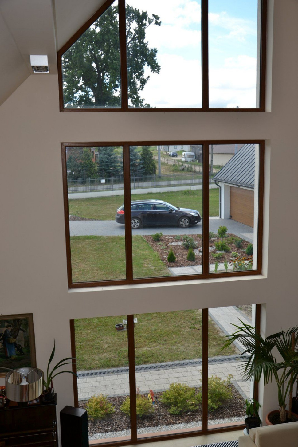 Pod wysokim przeszkleniem w salonie znajduje się grzejnik kanałowy z konwekcją naturalną