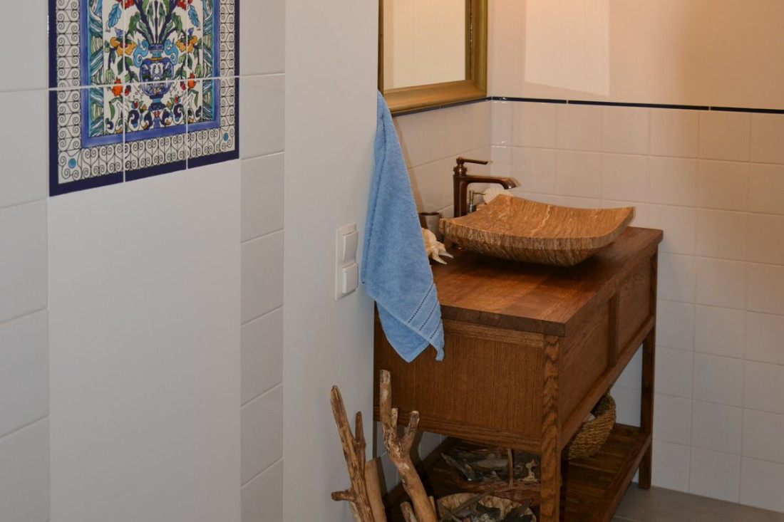 Łazienka z umywalką z trawertynu i armaturą w kolorze miedzianym