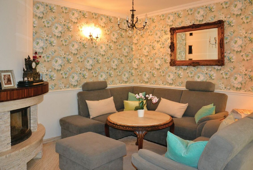 Część wypoczynkowa salonu, kominek i ozdobna tapeta na ścianach