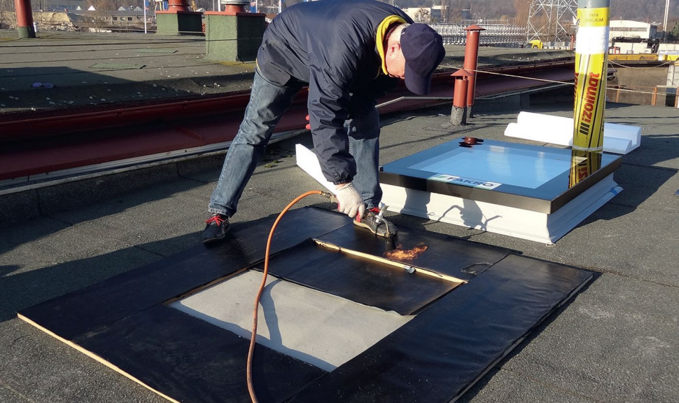 Nagrzewanie wierzchniej strony papy w celu stopnienia mikrofolii przed zamontowaniem okna