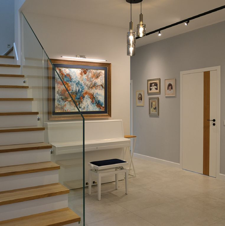 Dwubiegową klatkę schodową obrobili drewnem dębowym (stopnice), płytą MDF (podstopnice), zamówili balustradę ze szkła