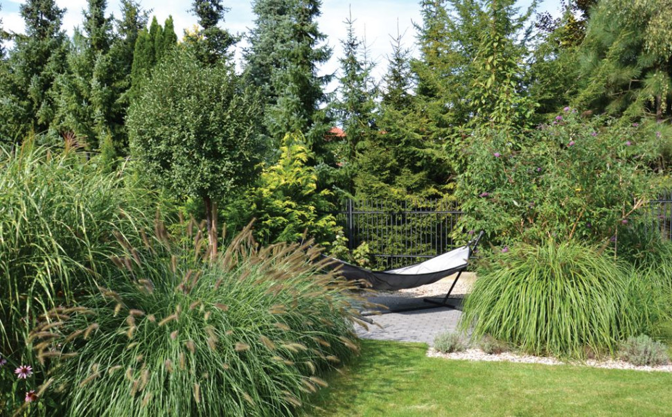 Placyk z hamakiem w ażurowy sposób zasłaniają m.in. rozrośnięte kępy traw o różnej wysokości, krzew omżynu (budleja Dawida) zwabiający motyle