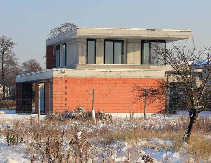 Dom o prostej bryle z płaskim dachem i dużymi przeszkleniami