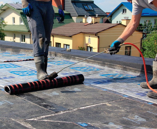 Układanie papy podkładowej na spadku dachu płaskiego, ukształtowanym ze styropapy, czyli ciętych według projektu płyt ze styropianu, fabrycznie oklejonych papą