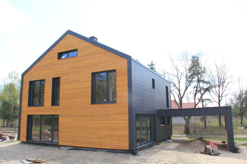 Duże przeszklenia z tyłu budynku, z prawej strony wiata garażowa