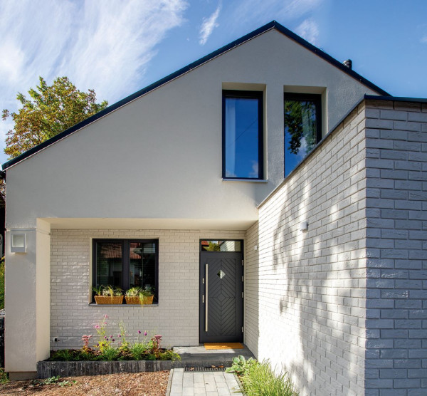 Elewację wykończono białym tynkiem silikatowym i białą okładziną betonową imitującą cegłę