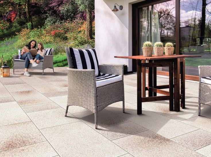 Taras wykończony modnymi ostatnio płytami ogrodowymi w wersji XXL, na nim meble z rattanu