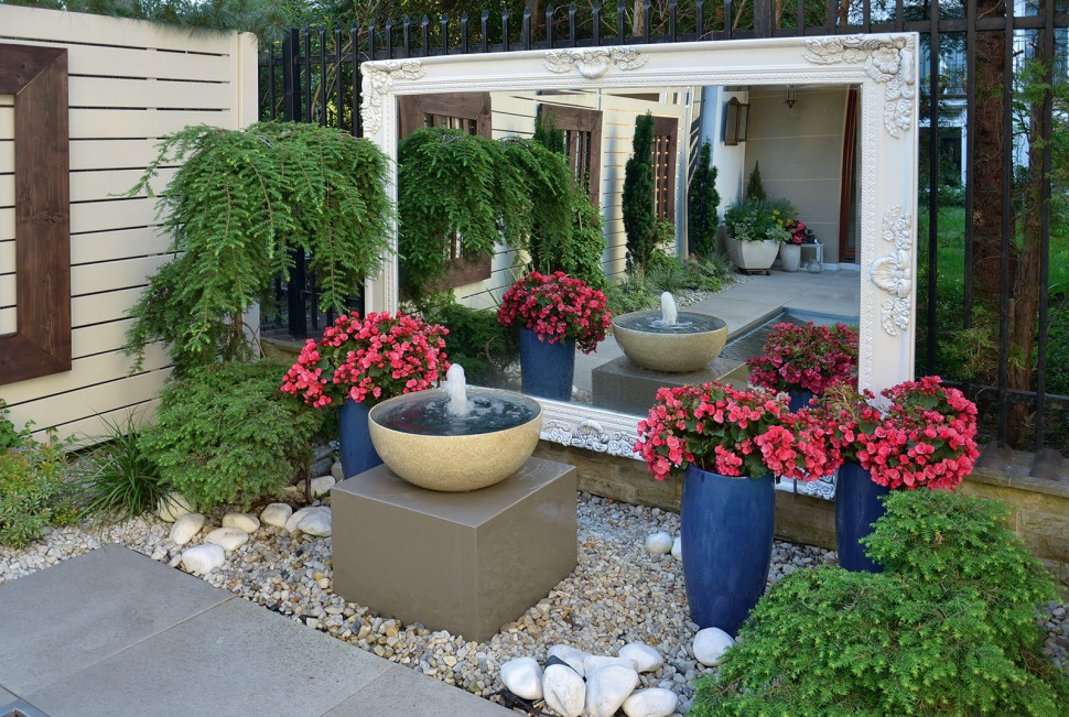 Fontanna na postumencie i duże lustro w ogrodzie