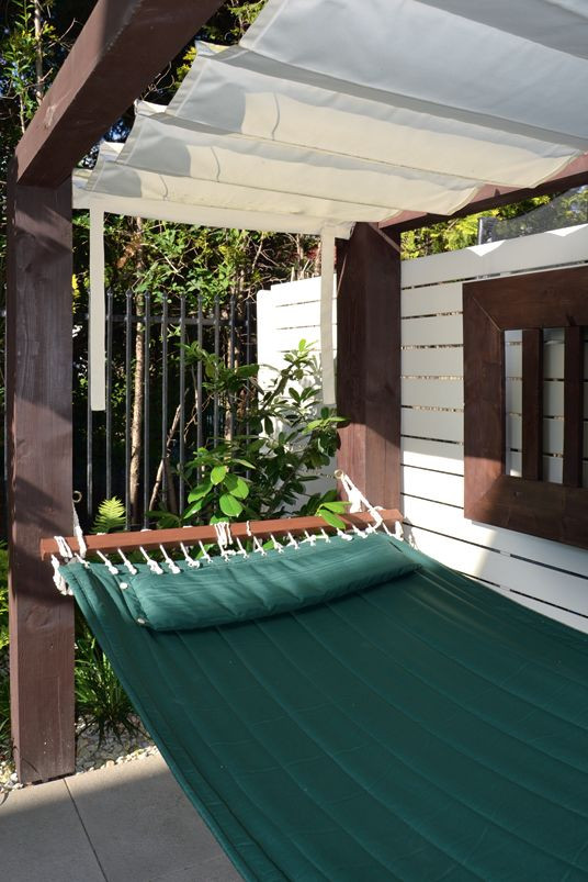 Szeroki hamak ułożony płasko i zawieszony za cztery rogi pergoli